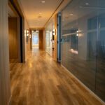 Modern office hallway with floor-to-ceiling glass partitions .