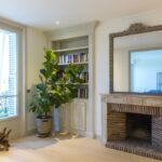Decorative framed mirror above a residential fireplace .