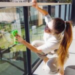 A woman demonstrates tips for cleaning glass railings at home using a microfiber cloth.