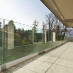 A frameless glass railing is used to create an aesthetically pleasing and functional protective barrier for the outdoor staircase.