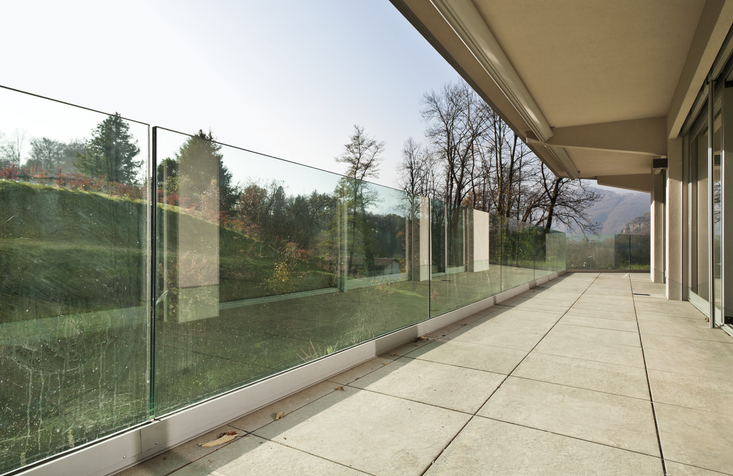 A frameless glass railing is used to create an aesthetically pleasing and functional protective barrier for the outdoor staircase.