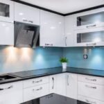 A sleek, contemporary kitchen with reflective light blue back painted glass colours used for the backsplash, demonstrating a fresh design trend to start the year with a modern home renovation.