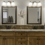 Two sparkling clean bathroom mirrors with elegant vanity lighting and a white floral centerpiece, serving as a perfect visual guide for how to clean mirrors and glass without leaving streaks.