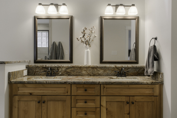 Two sparkling clean bathroom mirrors with elegant vanity lighting and a white floral centerpiece, serving as a perfect visual guide for how to clean mirrors and glass without leaving streaks.