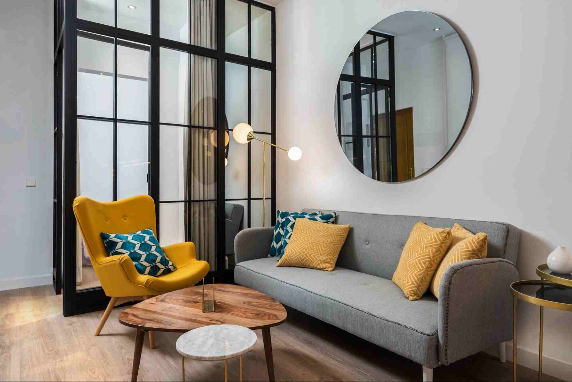 Modern living room with a round wall mirror above a sofa, showcasing stylish interior design elements relevant to acrylic mirror vs glass mirror comparisons.