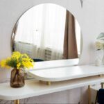 Frameless wall mirror mounted above a sleek vanity table, adding brightness and visual space to a minimalist home interior.