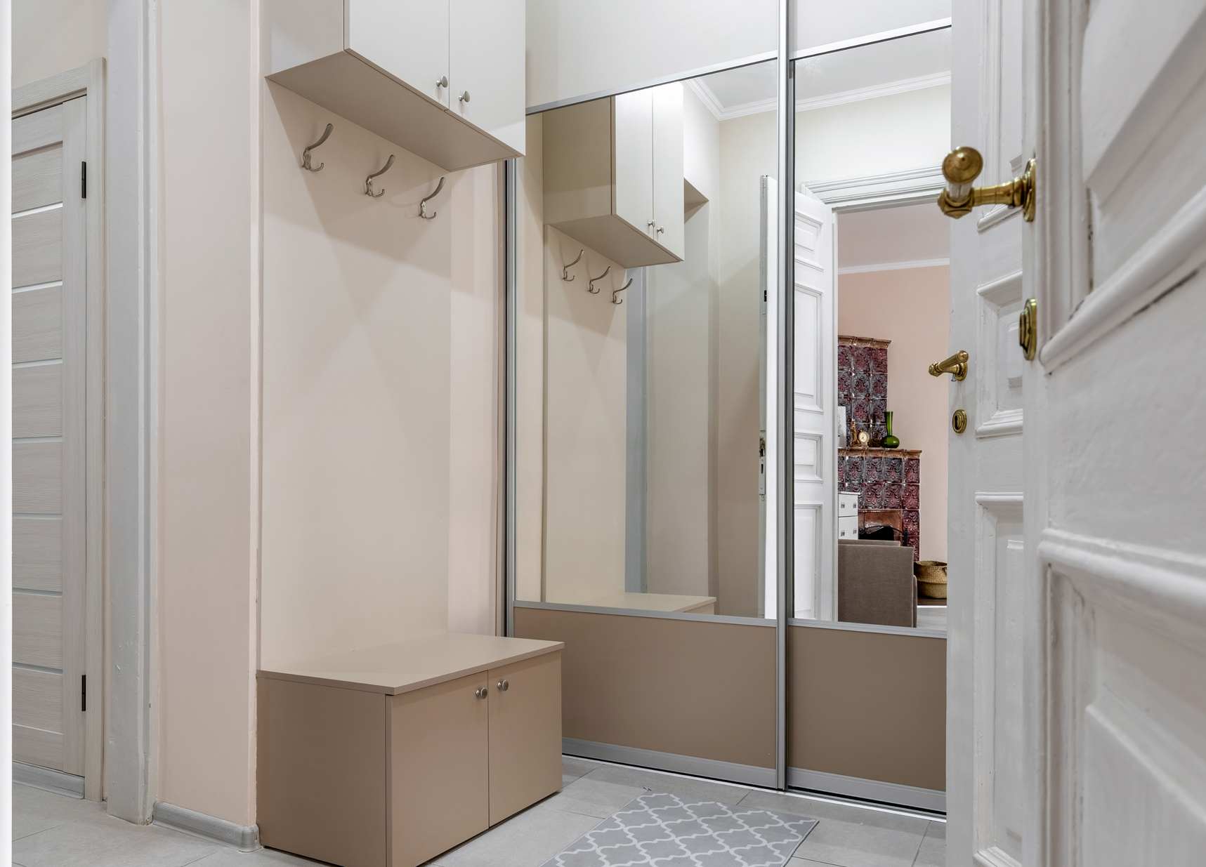 Two way mirror glass closet doors in a modern home entryway with built-in storage bench.