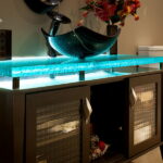 Custom kiln-formed glass countertop with integrated LED lighting and vessel sink for homeowners researching how much are kiln-formed glass countertops.