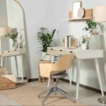 Large framed mirror with a light wood frame positioned beside a modern vanity desk in a bright contemporary home office, reflecting natural light and enhancing the sense of space.