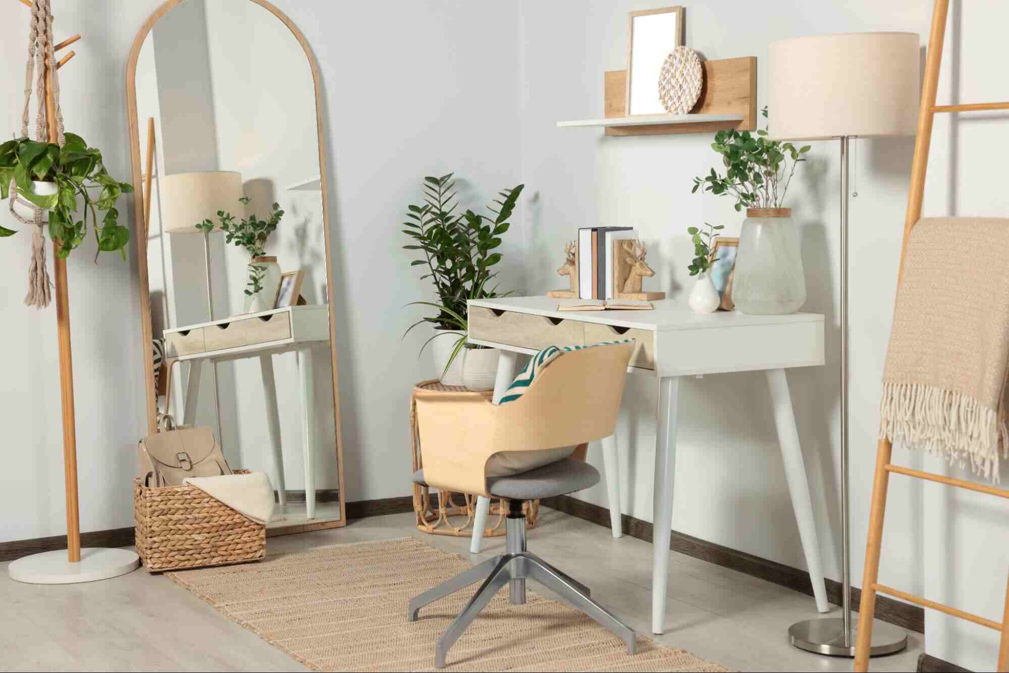 Large framed mirror with a light wood frame positioned beside a modern vanity desk in a bright contemporary home office, reflecting natural light and enhancing the sense of space.