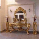 Ornate gold-framed antique mirror above an intricately carved console table in a luxurious foyer, showcasing the timeless elegance and craftsmanship of different types of antique mirrors in classic interior design.