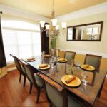 Dining room featuring decorative framed mirrors with warm wood furnishings.