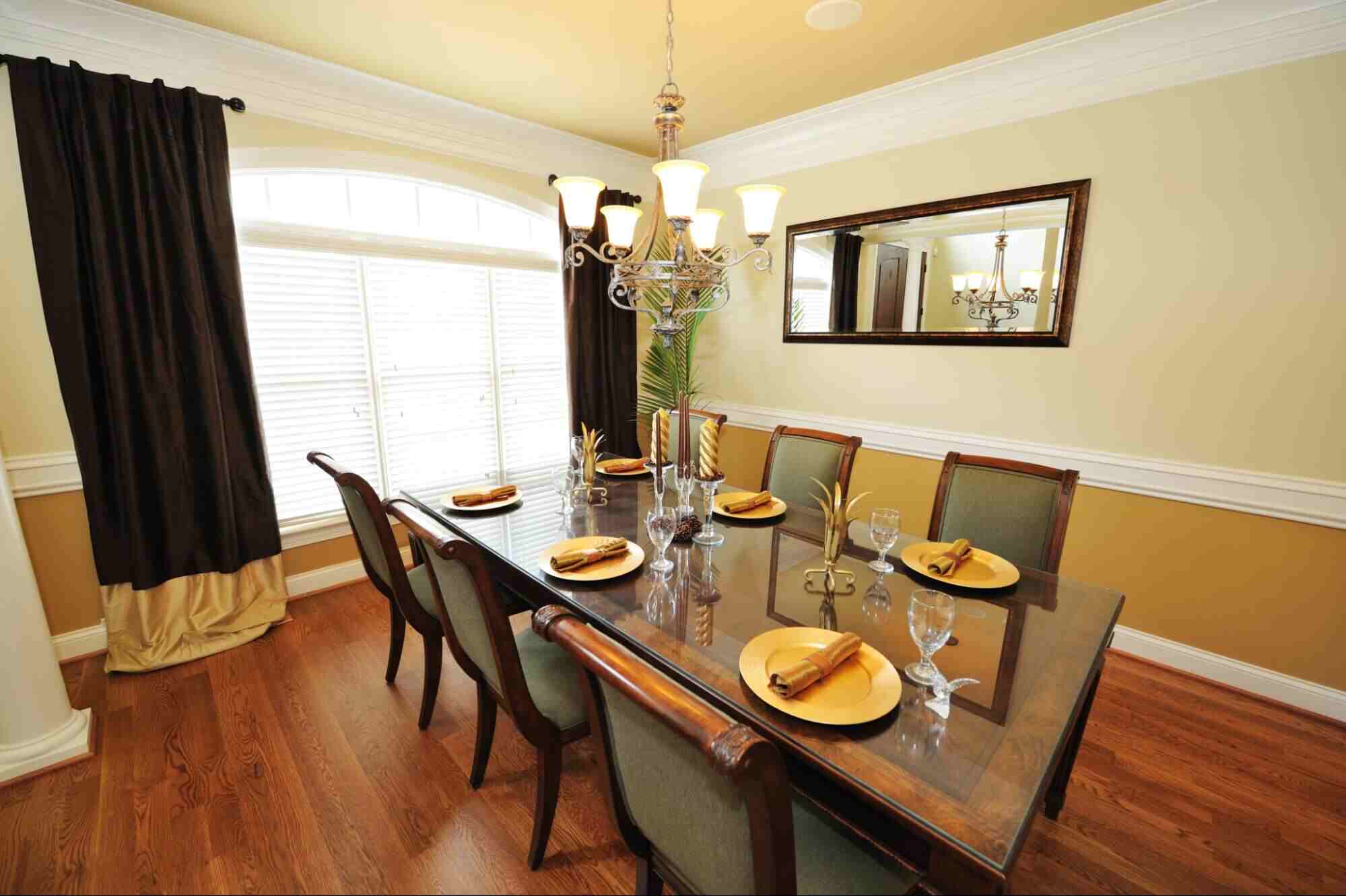 Dining room featuring decorative framed mirrors with warm wood furnishings.