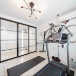 Home gym with glass partition walls separating the workout area from the adjoining space.