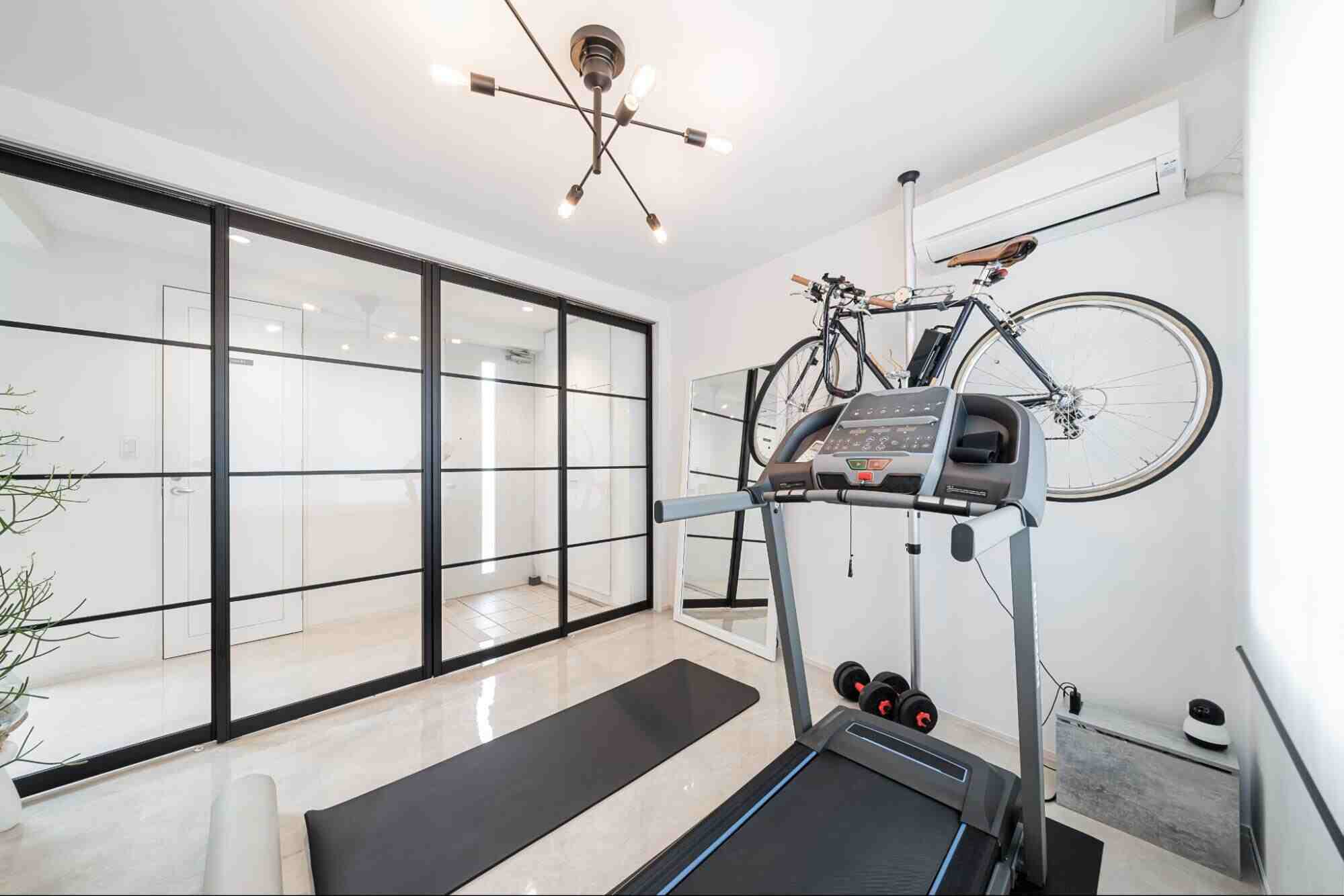 Home gym with glass partition walls separating the workout area from the adjoining space.